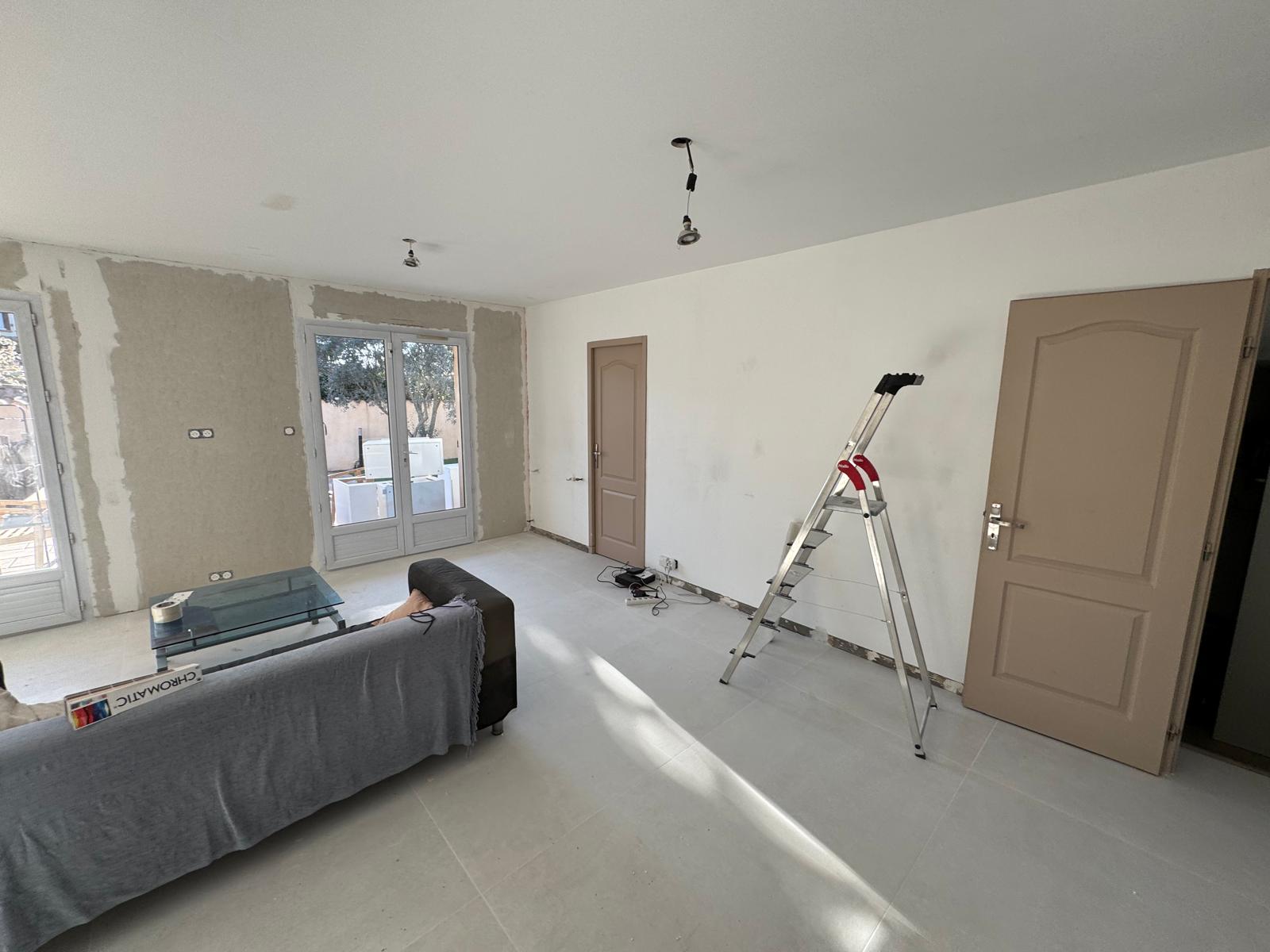 Chantier de rénovation d'un salon avec murs d'enduit et escabeau. Texte : CHROMATIC.